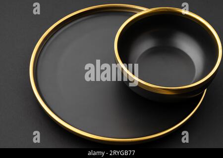 A set of black and golden ceramic plate and bowl on a black background Stock Photo