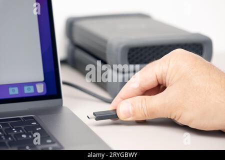 Hand connecting a External hard disk to a modern laptop computer Stock Photo