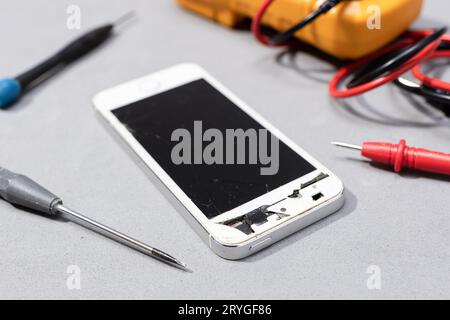 Smartphone with broken screen on electronic store workbench. Repairing damaged mobile phone concept Stock Photo