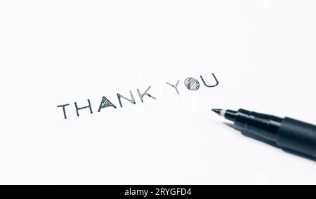 Thank you phrase made with stencil letters on white paper background. Copy space Stock Photo