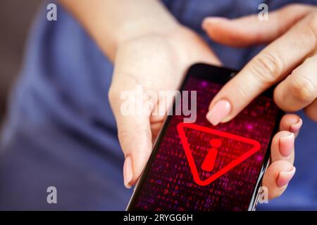 Mobile phone in female hands with screen showing compromised virus infected device. Cyber attack. Stock Photo