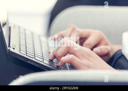 Young millennial woman typing on laptop. Closeup on hands. Day light dynamic workplace. Stock Photo