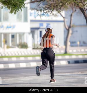 Ras Al Khaimah, UAE - February 5, 2022: African-american woman running on the street, active lifestyle Stock Photo