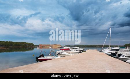 Pier with boats on the bay at sveti nikola fortres with dark clouds, sibenik Stock Photo