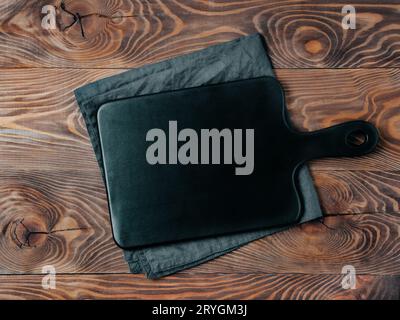 Black cutting board on wooden table, top view Stock Photo