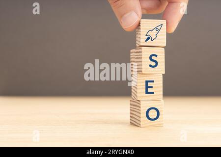 SEO or search engine optimization concept. Hand holding a wooden block with rocket icon and SEO word. Copy space Stock Photo