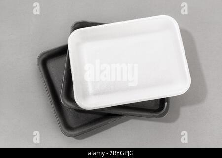 Group of styrofoam trays used for food. Black and white Disposable polystyrene trays isolated on gray background Stock Photo