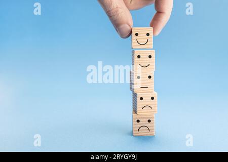 Customer service evaluation or satisfaction concept. Hand picked the happy face smile icon on wooden blocks. Copy space Stock Photo