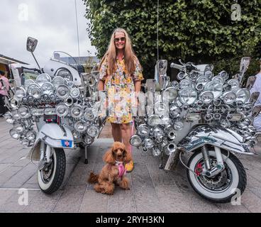 London, UK. 01st Oct, 2023. Lisa with her poodle Nancy standing next to two Mods scooters at the classic car Booth Sale in London - 30th Sept-1st Oct 2023.Paul Quezada-Neiman/Alamy Live News Credit: Paul Quezada-Neiman/Alamy Live News Stock Photo