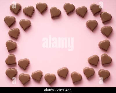Chocolate hearts confections frame on pink, copy space Stock Photo