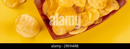 Potato chips or crisps, a salty snack on a yellow background Stock Photo
