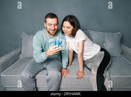 Young couple relaxing on sofa using mobile smart phone relaxing at home Stock Photo