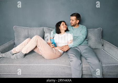 Smiling man hugging his wife relaxing on couch Stock Photo