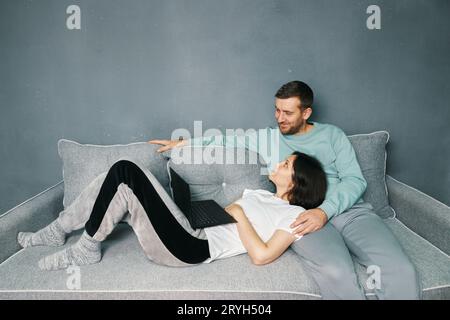 Happy couple embracing using laptop together relaxing on sofa at home Stock Photo