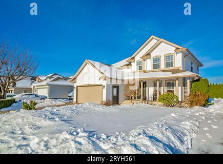 Family house with driveway and front yard in snow on winter sunny day Stock Photo