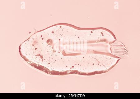 Liquid gel smear isolated on pink background. Beauty cosmetic smudge lotion, facial jelly serum, cleanser, shower gel or shampoo Stock Photo