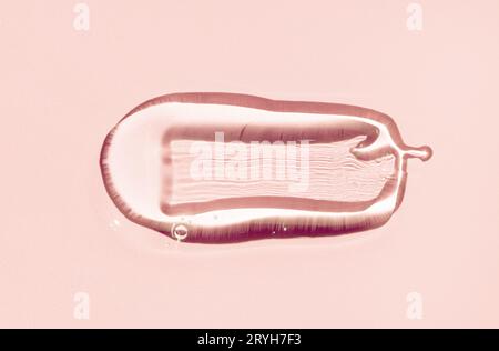 Close up of Serum drop texture. Clear liquid gel with bubbles drop isolated on pink background. Transparent cosmetic skincare pr Stock Photo