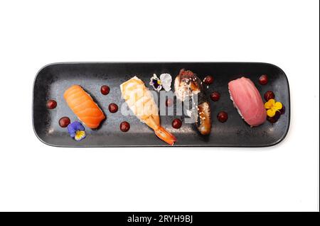 Nigiri sushi set with salmon, eel, tuna and shrimp, flat lay on black plate isolated. Traditional Japanese food, sushi restaurant menu. High quality p Stock Photo