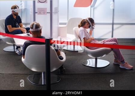Young woman using virtual reality headset while sitting in waiting room - Moscow, Russia, 05 September 2023 Stock Photo