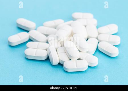 White medicine pills on blue background. Pharmacy background Stock Photo