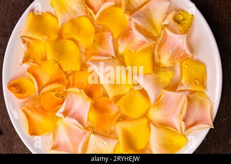 Top view of colorful rose petals floating on the surface of clear water in white ceramic bowl. Stock Photo