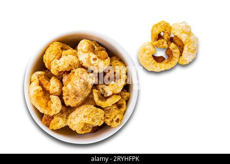 Top view (flat ray) of crispy homemade delicious deep fried pork rinds in white ceramic bowl isolated on white background. Stock Photo