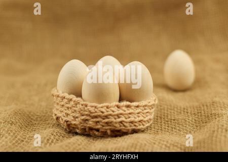 Decorative wooden Easter eggs in a wicker basket. Chicken eggs closeup on a vintage background. Zero waste easter. Stock Photo