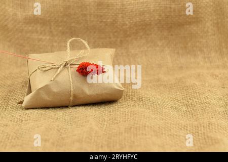 Vintage gift box brown paper wrapped in craft paper and tie hemp cord. Craft gift with rope on burlap background. Stock Photo
