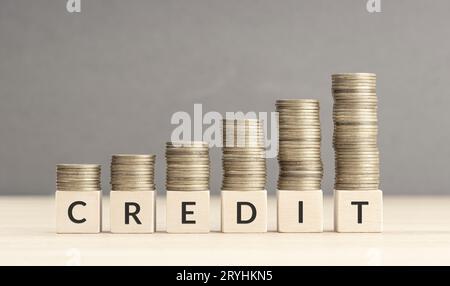 Credit increasing concept. Text word on wooden blocks with coins stacked in increasing stacks. Copy space Stock Photo