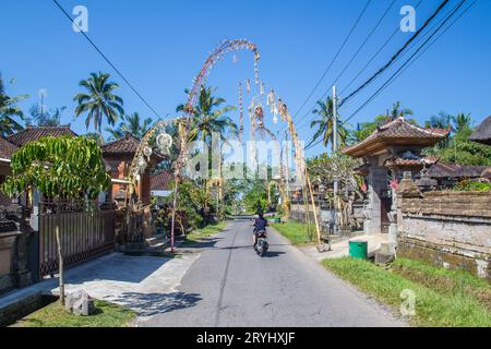 BALI, INDONESIA - 16TH APRIL 2017:  Streets in Bali. Penjor Poles can be seen as part of the annual Galungan Celebration. People can be seen. Stock Photo