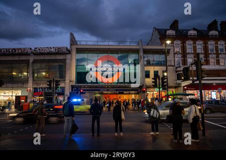 Brixton, London, UK: Pedestrian crossing on Brixton Road opposite Brixton underground station. Evening view with people, traffic and a police car. Stock Photo