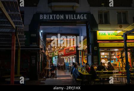 Brixton, London, UK: Entrance to Brixton Village at night. Brixton Village consists of covered streets with restaurants and shops. Stock Photo