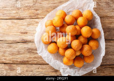 quail egg-shaped fried sweet potato balls deep fried in oil closeup on the wooden table. Horizontal top view from above Stock Photo