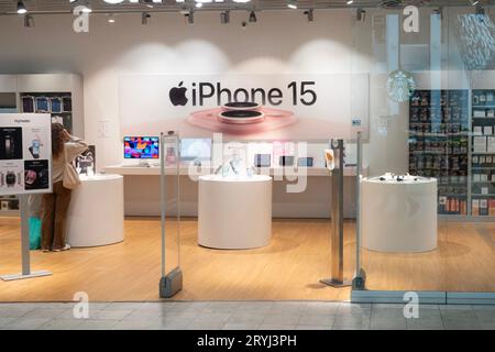 Store selling Apple products with large sign advertising for iPhone 15. Copenhagen, Denmark - October 1, 2023. Stock Photo