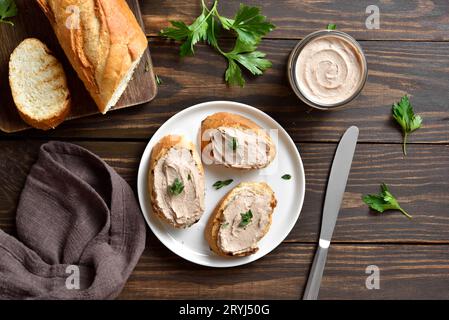 Toasted bread with chicken liver pate over wooden background. Top view, flat lay Stock Photo