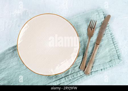 An empty white plate with a gold rim, with a fork and a knife Stock Photo