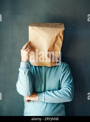 Man with a paper bag on head pointing to head with one finger Stock Photo