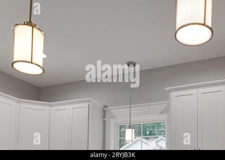 Vintage Chrome Kitchen Pendant Lights in Set of Three with White Cabinets Stock Photo