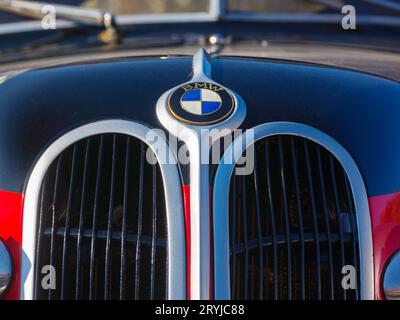 bmw ornament shining on the black hood of a red 321 oldtimer. outdoor close up Stock Photo