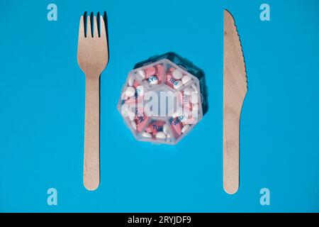 Organizer weekly shots with fork and knife medical pill box with doses of tablets for daily take medicine with white pink drugs Stock Photo