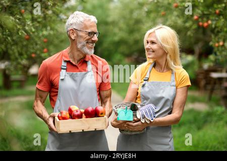 Portrait Of Happy Mature Farmer Spouses Walking In Fruit Orchard Together Stock Photo