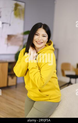 Mature Asian woman is captured in her home, enjoying the happy moments of life through the lens of lifestyle biohacking. She is Stock Photo