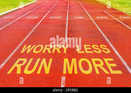 Worry Less Run More written on rubberized running track Stock Photo