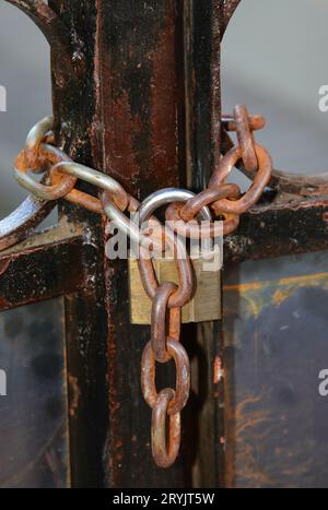 large padlock with rusty chain that securely closes an iron gate Stock Photo