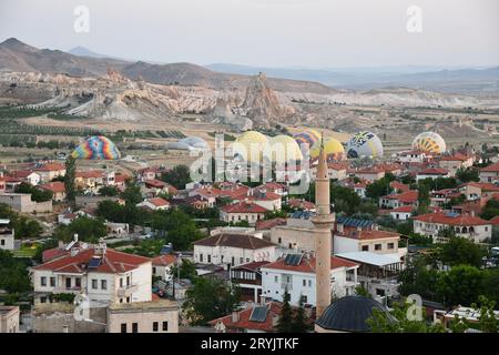 Aerial view of the village of Cavusin, the minaret and hot air balloons in the background in Turkey Stock Photo