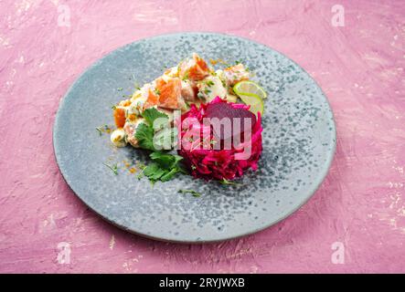 Traditional steamed and diced salmon fillet salad with red beet relish served as close-up on a Nordic Design plate with text spa Stock Photo