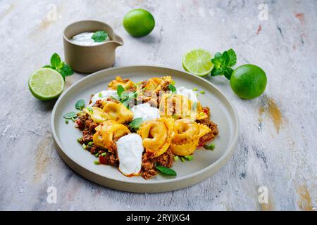 Traditional oriental manti dumplings with spicy minced meat and yogurt served as close-up on a Nordic design plate Stock Photo