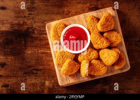 Chicken nuggets with ketchup on a rustic wooden table, shot from the top Stock Photo