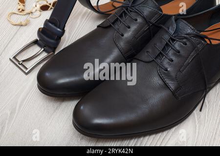 Pair of black leather men's shoes and leather belt for men on the floor. Stock Photo