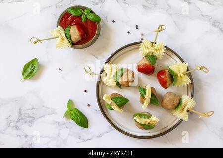 Birthday or romantic dinner. Pasta cooked in the form of canapes, meatballs, served with tomato sauce on a marble countertop. To Stock Photo